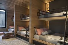 bunk beds in a room with wooden walls and carpeted flooring next to a window