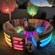 an outdoor seating area is lit up with colorful lights and pillows on the couches