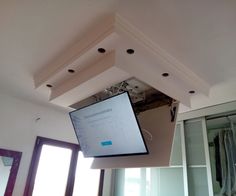 a projector screen suspended from the ceiling in a room with closet doors and windows