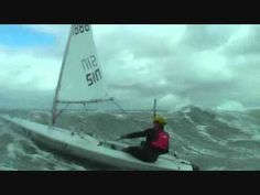 a man riding on the back of a sailboat in rough ocean water with waves