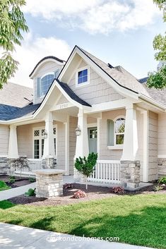 a house with white trim and gray shingles on the front, grass in front