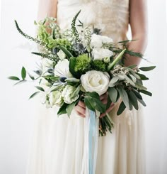 a bride holding a bouquet of white and green flowers