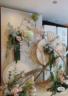 an arrangement of flowers and paper lanterns on the wall