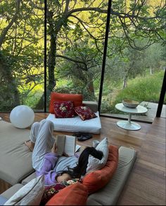 a woman laying on top of a couch in a living room next to a window