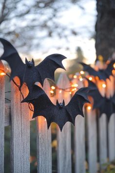 some bats are hanging on the fence with fairy lights around them and they look like they're ready to fly