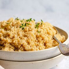 a white bowl filled with rice and garnished with parsley next to a spoon