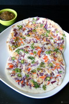 two flatbread pizzas on a white plate next to a small bowl of salsa