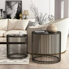 two black metal tables sitting on top of a wooden floor next to a white couch