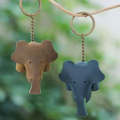 two small elephant key chains hanging from a tree