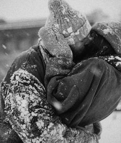 black and white photograph of a person in the snow with their arms wrapped around each other