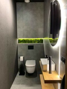 a bathroom with a toilet, sink and green plants in the window sill on the wall