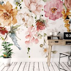 a desk and chair in front of a wall with flowers painted on the wall behind it