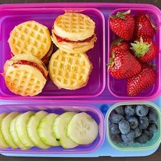 a plastic container filled with fruit and waffles on top of a wooden table