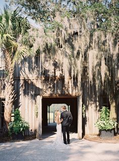 a bride and groom standing in front of an old barn with spanish moss growing on it