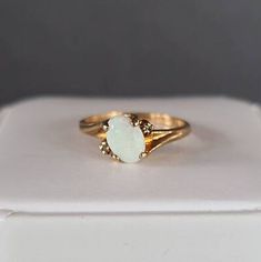 a gold ring with a white opal stone on the front, and an open band around it