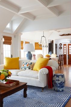 a living room with white couches and yellow pillows on top of the sofas