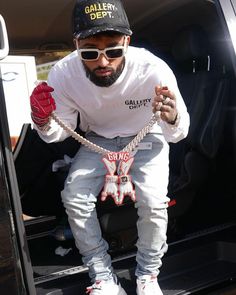 a man sitting in the back of a van with chains on his feet and wearing sunglasses