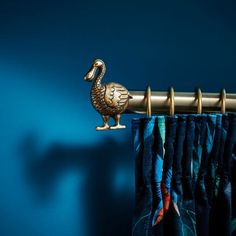 a curtain rod with a gold goose on it's side hanging from a blue wall