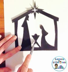 someone is cutting out the silhouette of a nativity scene with scissors and glue on paper