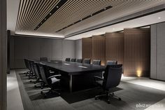 an empty conference room with black chairs and wooden paneled walls, along with a long table