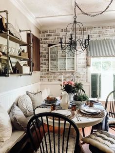 a dining room table with chairs and plates on it in front of a brick wall