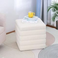 a stack of folded towels sitting on top of a white ottoman