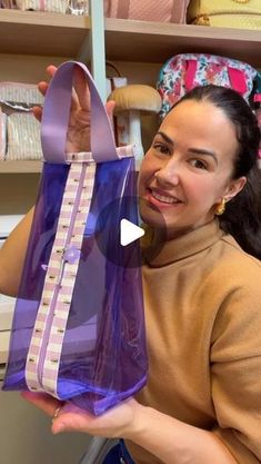 a woman holding up a purple bag in front of her face and smiling at the camera