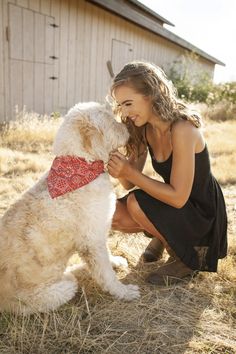 a woman kneeling down next to a white dog