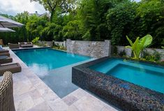 an outdoor swimming pool surrounded by lounge chairs and umbrellas with trees in the background