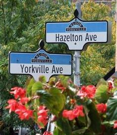 two blue and white street signs sitting on top of a pole next to some flowers