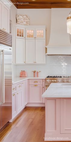 a kitchen with pink cabinets and white counter tops, wood floors and a chandelier