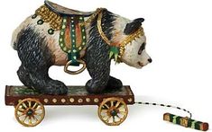 a bear figurine is sitting on top of a toy wagon with wheels and chains