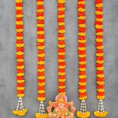 an arrangement of orange and yellow garlands with ganeshi idol on the side