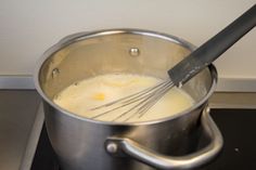 a large metal pot filled with liquid and whisk on top of a stove