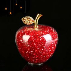 an apple with glitter on it sitting in front of a black background