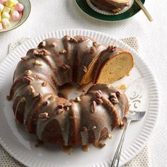 a bundt cake with frosting and nuts is on a plate next to a fork