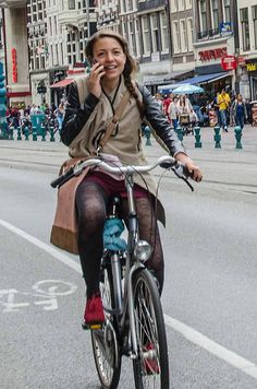 a woman riding a bike while talking on her cell phone