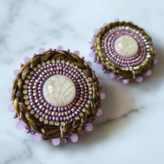 Indigenous made purple and gold stud earrings with sweetgrass braid. Gold Woven Earrings As A Gift, Artisan Woven Earrings For Gift, Handmade Lavender Beaded Earrings For Gift, Artisan Woven Earrings As Gift, Round Woven Earrings Ideal For Gifts, Woven Round Earrings Perfect For Gifts, Handwoven Round Earrings For Gift, Round Woven Earrings For Gift, Purple Handwoven Earrings As A Gift