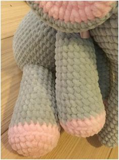 a gray and pink teddy bear sitting on top of a wooden floor