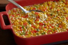 a red casserole dish filled with corn and vegetables