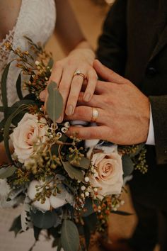 the bride and groom are holding each other's hands with wedding rings on their fingers