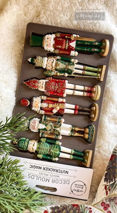 an assortment of wooden russian dolls in a box on a white carpet with pine branches