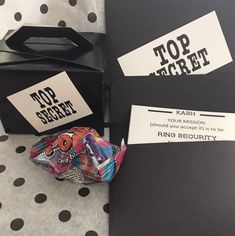 two black boxes with top secret cards and a candy bar in front of them on a polka dot tablecloth