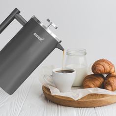 coffee being poured into a cup next to croissants