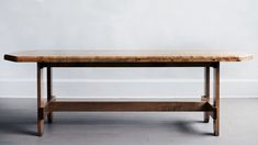 a wooden table sitting on top of a hard wood floor next to a white wall