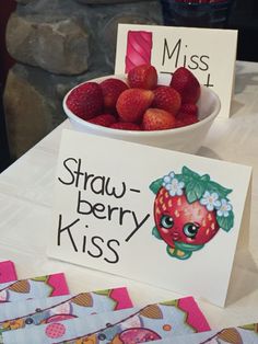 strawberries are in a bowl on a table with two signs that say miss 1