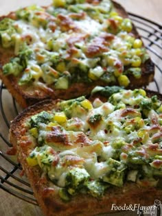 two pieces of bread with broccoli and cheese on them sitting on a wire rack