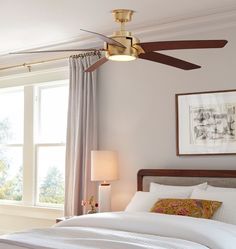 a bedroom with a bed, ceiling fan and window in the corner next to it