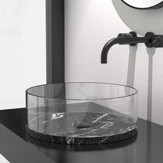 a bathroom sink with a circular glass bowl on the counter top next to a round mirror