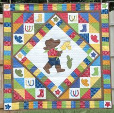 a colorful quilt with a bear holding a baseball bat on it's back and the letters u in different colors